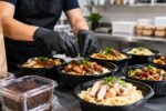 Cardápio para dark kitchen com bowls de frango, massas e embalagens de delivery em cozinha moderna iluminada