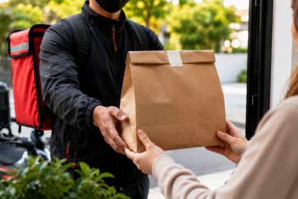 Entregador entrega pacote de comida em casa, representando delivery em casa e início da formalização com CNPJ.